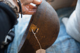 Carved geometric patterns and golden metal repair on an antique African wooden bowl.