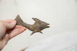 A vintage African bronze fish held in hand, displaying its rustic handmade details.