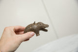 Handmade African bronze hippo showing its textured patina and scale in hand.