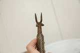 Hand holding vintage African bronze antelope, revealing etched concentric circle patterns.