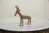 Side view of a handmade vintage African bronze antelope showing its textured body.