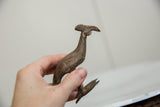 Hand holding the vintage African bronze bird sculpture, showing its scale and textural details.