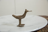 Vintage African bronze bird sculpture showing its textured patina, flat bill, and stylized shape.