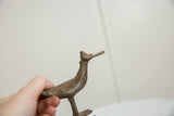 Vintage African bronze bird held in hand, showing its textured surface from a low angle.