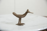 Side view of a vintage bronze bird highlighting its long, flat bill and rustic texture.