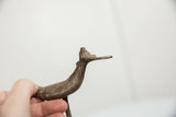 Profile view of a vintage bronze bird's head and flat bill with aged patina.