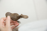 Overhead view of a vintage bronze bird's textured body and distinctive flat bill.