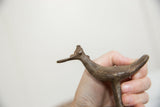 Vintage African bronze bird held in hand, showing its scale and textured surface.