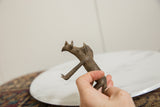 Side profile of a vintage bronze warthog held to show its handmade texture and scale.