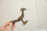 A hand holds the vintage African bronze bird, illustrating its scale and long-tailed form.