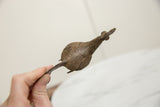 Vintage bronze bird held in hand, showing the incised textural detail along its back.