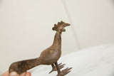 Low angle view of the vintage bronze bird showing its textured body and crested head.