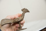 Vintage African bronze bird held to show its handmade texture and scale.