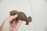 Vintage African bronze chameleon held in hand, showing intricate texture and curled tail.