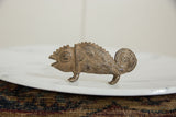 Profile view of a vintage bronze chameleon showing its detailed, textured body and coiled tail.