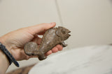 Profile view of a vintage bronze chameleon highlighting its textured scales and curled tail.