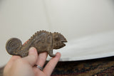 Hand holding vintage African bronze chameleon, detailing its textured body and sculpted eye.