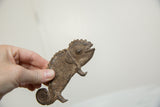 Hand holding vintage African bronze chameleon, showing detailed scales and aged patina.
