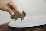 Vintage African bronze chameleon sculpture held in hand, showcasing textured details.