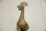 Side profile of a vintage bronze bird's head, featuring a textured patina and crest.