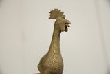Profile of a vintage bronze bird's head showing its textured patina and prominent comb.