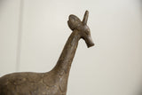 Profile view of a vintage bronze giraffe's head with etched patterns and hand-worked features.