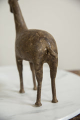 Bronze giraffe figurine's back showing aged patina and etched circular patterns.