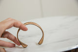 Antique African copper bracelet held to show its open cuff shape and hand-forged texture.