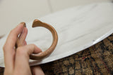 Antique copper cuff bracelet held to show its handcrafted form and warm aged patina.