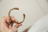 Profile of the antique copper snake bracelet showing its open cuff and smooth patina.