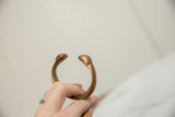 Antique copper snake bracelet held open, showing its handmade cuff form and aged patina.