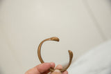 Antique African copper snake bracelet held, showing its open cuff and smooth patina.