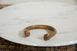Profile of an antique African copper bracelet highlighting its substantial form and warm, aged patina.
