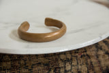 Side view of the antique copper bracelet's open cuff and time-softened patina.