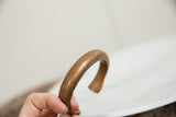 Smoothly curved form and time-softened patina of the antique copper bracelet.
