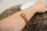 Antique copper snake bracelet worn on the forearm, displaying its scale and smooth, aged patina.