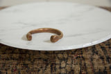 Angled view of a handmade antique copper bracelet showing its open form and aged patina.