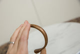 The curved profile and aged patina of an antique copper snake bracelet held in hand.