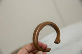 Angled view of the antique copper bracelet highlighting its stamped pattern and form.