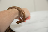 Antique copper snake bracelet with textured details worn on the wrist.