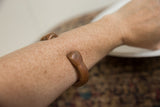 The antique African snake bracelet worn on a forearm, showing its aged copper finish.