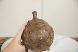 A hand holding the vintage bronze turtle, showing its textured, patterned shell.