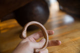 A hand holds the antique copper cuff, showing its substantial form and warm, aged patina.