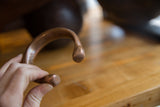 A hand holding the antique copper snake cuff, highlighting its smooth, rounded ends.
