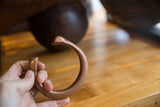 The substantial, curved form of a handcrafted antique copper snake cuff shown in profile.