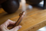 A hand holding the rounded, hand-formed end of an antique copper snake bracelet.