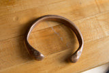 The smooth, curved band and open design of the antique copper snake cuff.