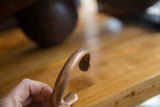 Antique copper cuff held to show its smooth, substantial curve and aged patina.