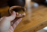 Stamped dot details on the handcrafted snake head of an antique copper cuff.