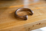 Side profile of the antique copper snake cuff, highlighting its sculptural form and warm patina.
